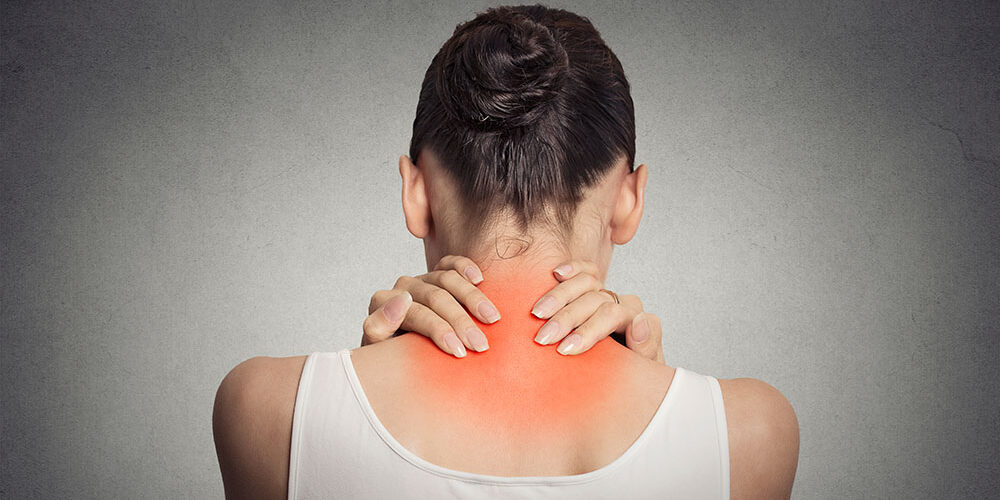 Healthy lifestyle. Back and spine disease. Closeup back view tired female massaging her neck colored in red isolated on gray background